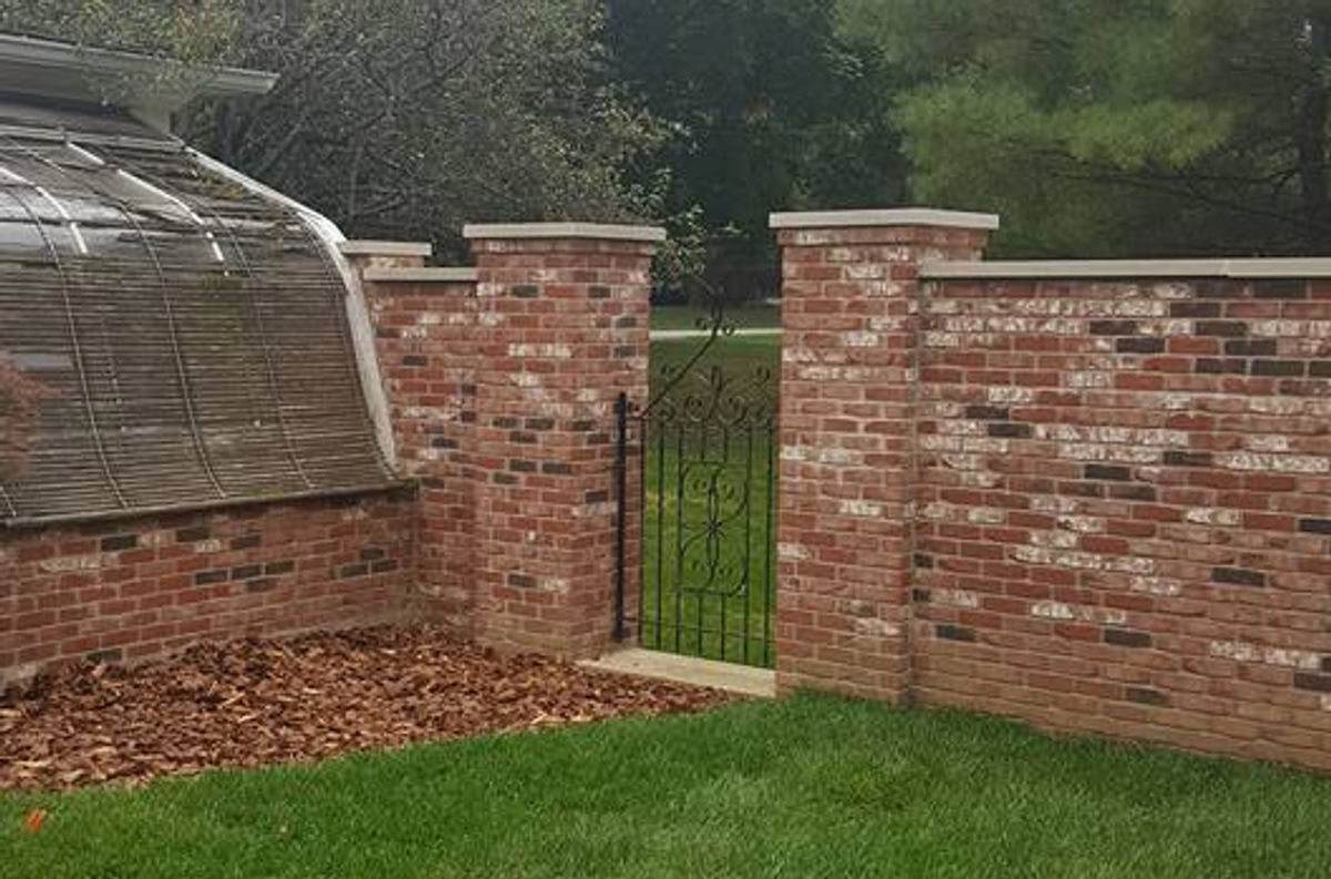 Brick privacy wall with iron gate and brick pillars