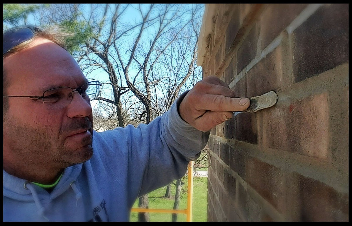 Tim Phipps tuckpointing a brick wall by hand